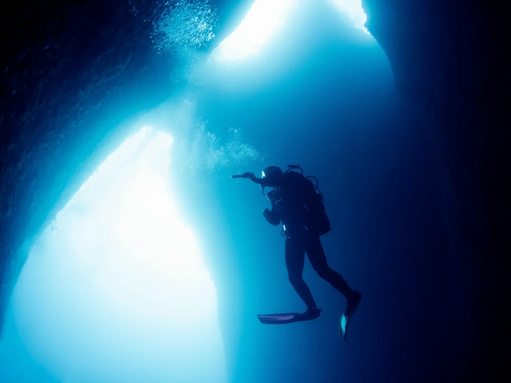 scuba-divers-with-flashlight-swimming-in-dark-cave